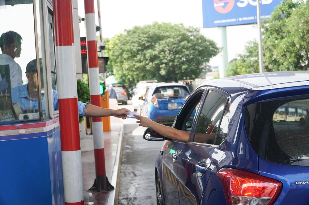 Tại làn thu phí thủ công, nhiều phương tiện được hướng dẫn vào khu vực dán thẻ định danh xe ô tô để sử dụng dịch vụ thu phí điện tử không dừng.