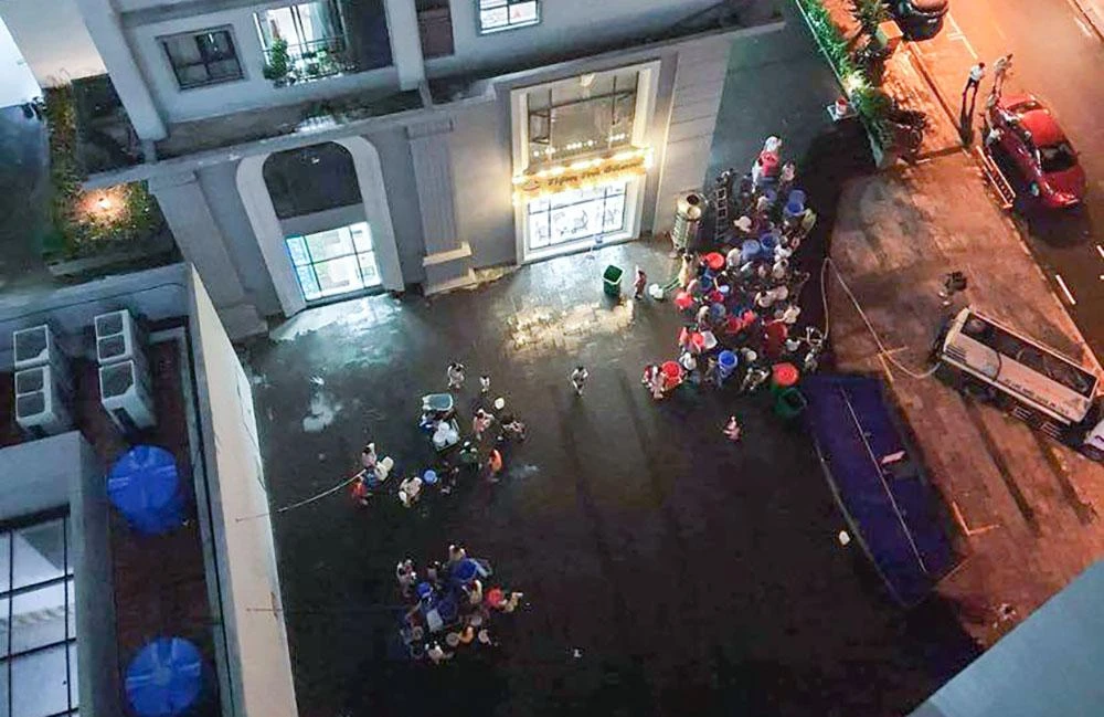 Hơn 23 giờ đêm 23-9, rất đông cư dân sống tại chung cư Hateco, phường Phương Canh, Nam Từ Liêm, Hà Nội vẫn kiên trì đứng xếp hàng để chờ lấy được ít nước sạch mang lên sử dụng.