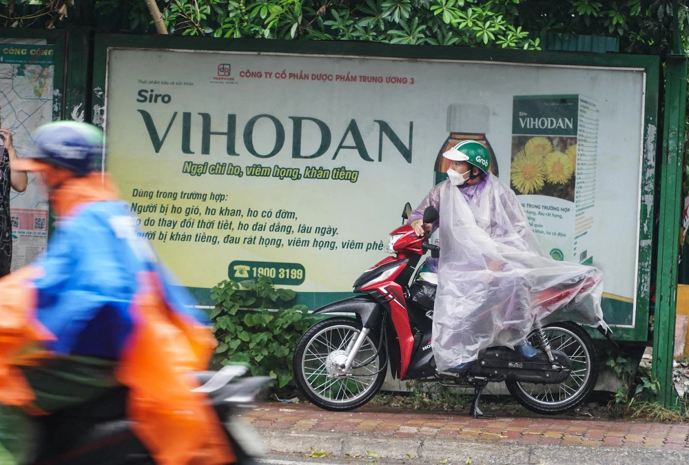 Một tài xế xe ôm thu mình trong một điểm đón buýt trên đường Phạm Hùng trong lúc chờ đợi khách.