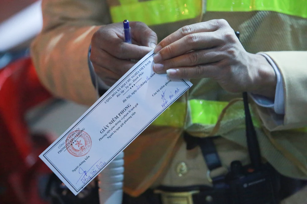 Xe vi phạm được lực lượng chức năng dán giấy niêm phong, trong đó có chữ ký của người chứng kiến và cán bộ xử lý vi phạm.