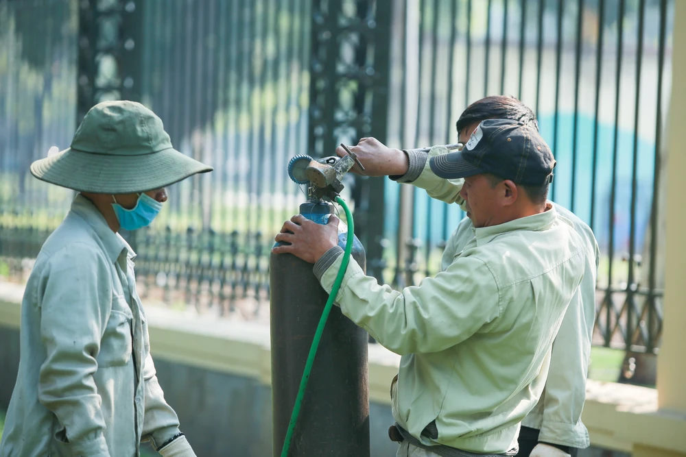 Các công nhân cùng máy móc, thiết bị tham gia cắt, tháo dỡ phần trụ sắt trên các cột bê tông. Sau khi dỡ đoạn rào phía đường Trần Nhân Tông, dài khoảng 400m, việc đảm bảo an ninh trật tự khu vực sẽ do lực lượng công an đảm nhận.