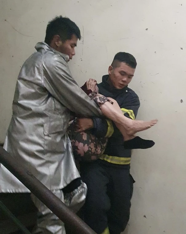 Lực lượng chữa cháy đưa cụ già thoát khỏi đám cháy an toàn. Ảnh CACC