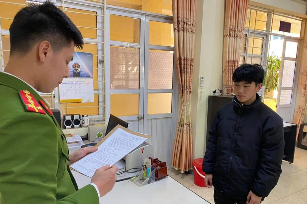 Hoàng Hảo Đông (tay phải) nghe cơ quan công an đọc quyết định khởi tố. Ảnh CACC