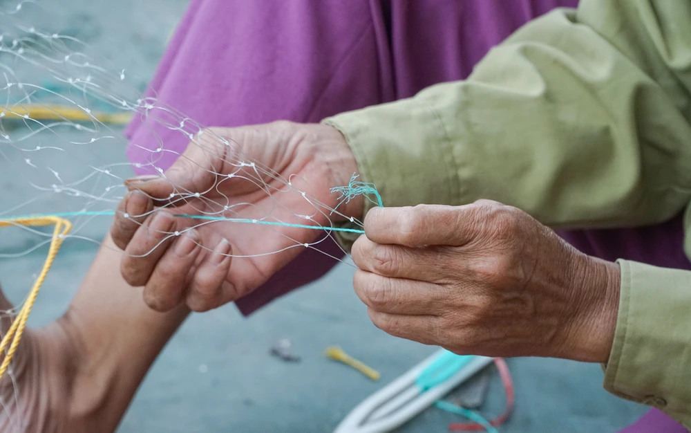 Những tấm lưới đang được bà Nga vá lại để đảm bảo chắc chắn cho lần ra khơi sắp tới.