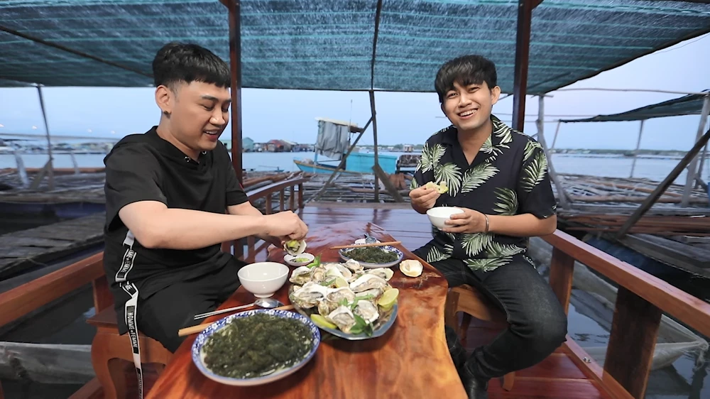 Hai nhân vật cùng ăn các món ăn tại làng bè Long Sơn.