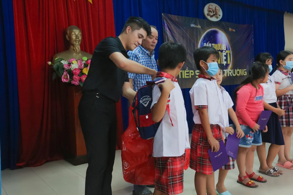 Bảo Hoàng tặng cặp cho mấy em học sinh.