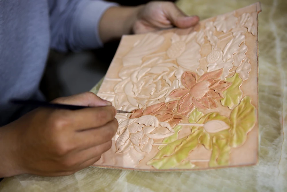 Sau khi điêu khắc, anh Tuấn sẽ lên màu cho sản phẩm. Anh Tuấn dùng màu batik chuyên nhuộm da. Để có được chất màu đậm đà, anh Tuấn cần đợi sản phẩm khô sau đó tô chồng thêm lớp màu.