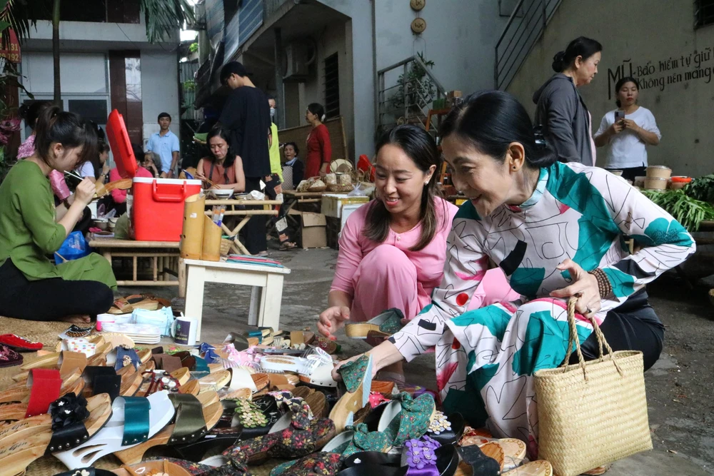 Bà Trần Thị Thanh Hương (56 tuổi, bìa phải) ngụ tỉnh Long An tìm lựa những đôi guốc có hoa văn đẹp mắt, dễ phối đồ. "Cảm xúc của tôi bây giờ thật sự dâng trào, tôi như được trở về với bản gốc chân chất, chân quê của mình. Tôi muốn lưu giữ lại nét truyền thống của quê mình. Mình phối hợp nét hiện đại trong tạo hình đôi guốc sẽ giúp cho đời guốc thêm dài lâu”. - Bà Hương nói.