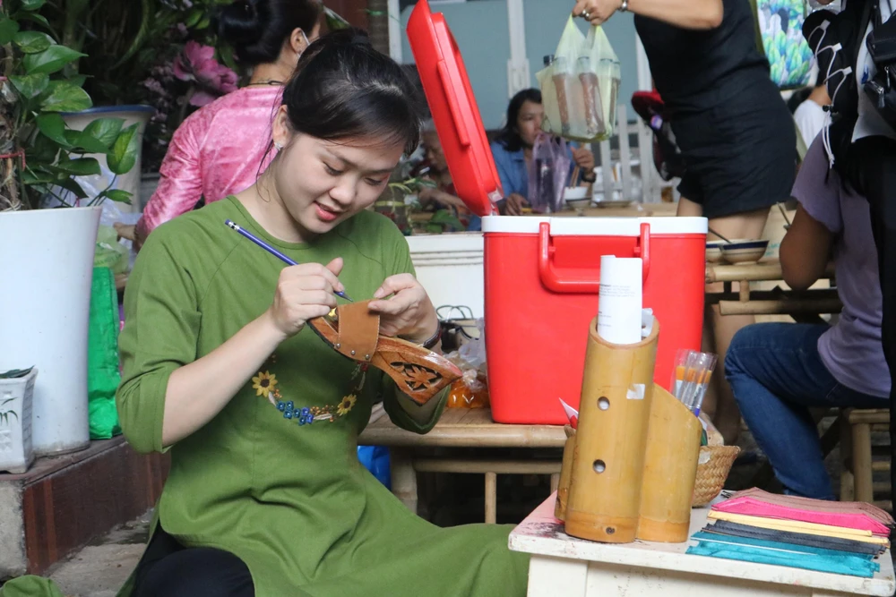 Chị Bùi Thị Thu Nguyên (30 tuổi, quận Bình Thạnh, TP.HCM) đảm nhận công việc hướng dẫn, vẽ trang trí lên đôi guốc. Là giáo viên dạy vẽ của trường mầm non, chị Nguyên rất thích được ứng dụng hoa tay của mình lên sản phẩm truyền thống là đôi guốc mộc.
