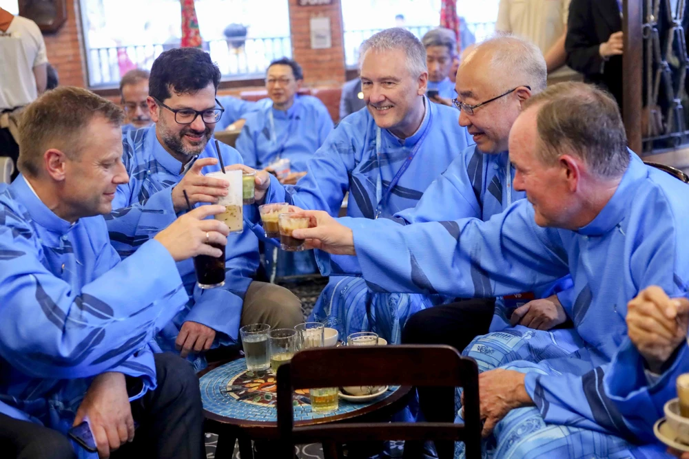 Đại biểu quốc tế mặc dài thưởng thức cà phê trứng