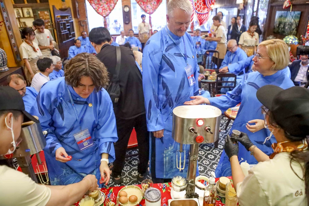 Đại biểu quốc tế mặc dài thưởng thức cà phê trứng