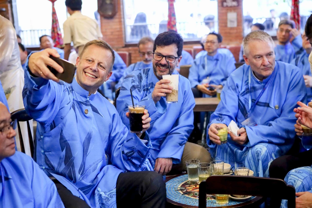 Đại biểu quốc tế mặc dài thưởng thức cà phê trứng