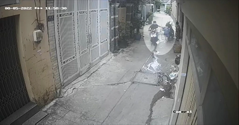 Nam thanh niên chạy xe máy cướp giật iPad trên tay bé trai trong con hẻm. Ảnh chụp từ clip