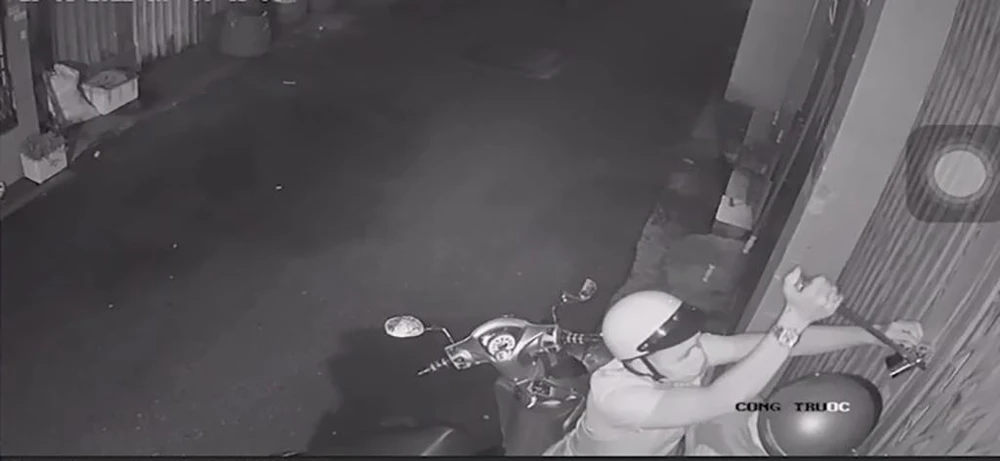 Một người dùng dụng cụ cạy khóa cửa. Ảnh chụp từ clip