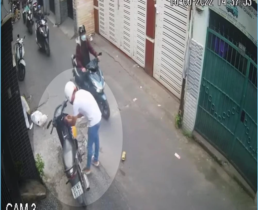 Nam thanh niên thản nhiên dùng đoản phá khóa mặc cho người đi đường qua lại. Ảnh chụp từ clip