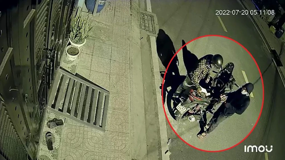 Sau đó, cả hai cùng đứng mở cốp xe máy kiểm tra, vứt lại giấy tờ không có giá trị. Ảnh chụp từ clip