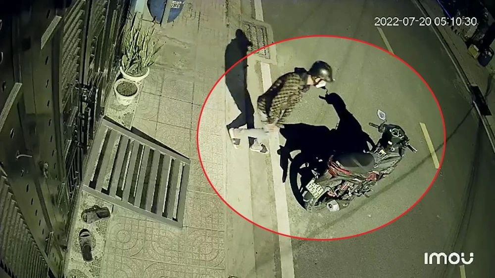 Sau khi đột nhập nhà trọ, nam thanh niên thản nhiên dắt xe máy của anh H ra ngoài rồi đứng đợi đồng bọn. Ảnh chụp từ clip