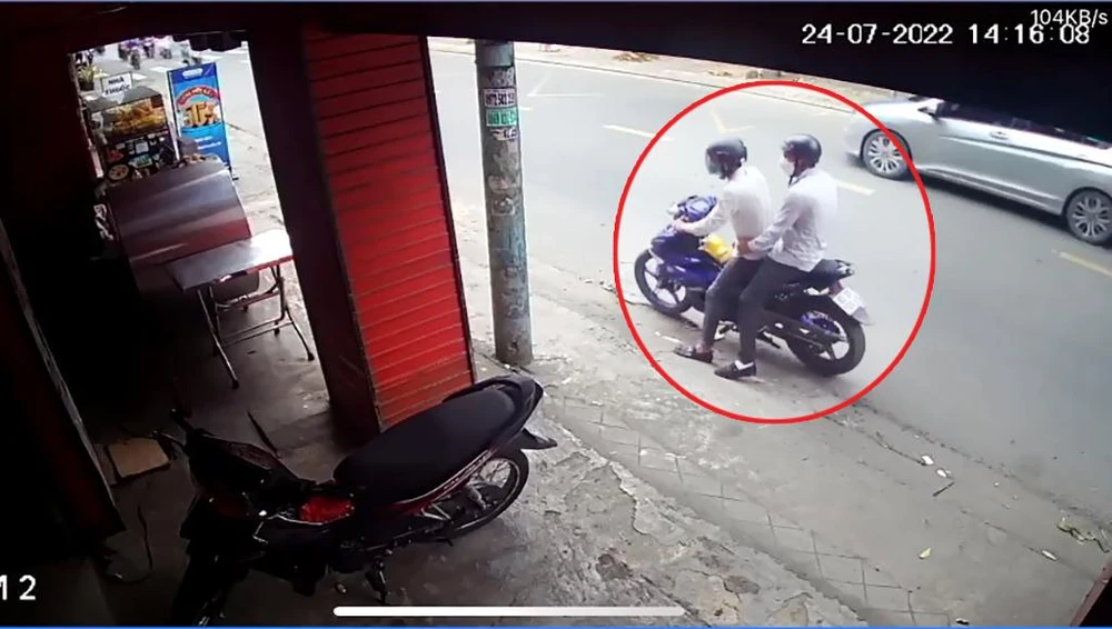 Hai nam thanh niên ăn mặc lịch sự tiếp cận xe máy của chị H rồi trộm cắp. Ảnh chụp từ clip