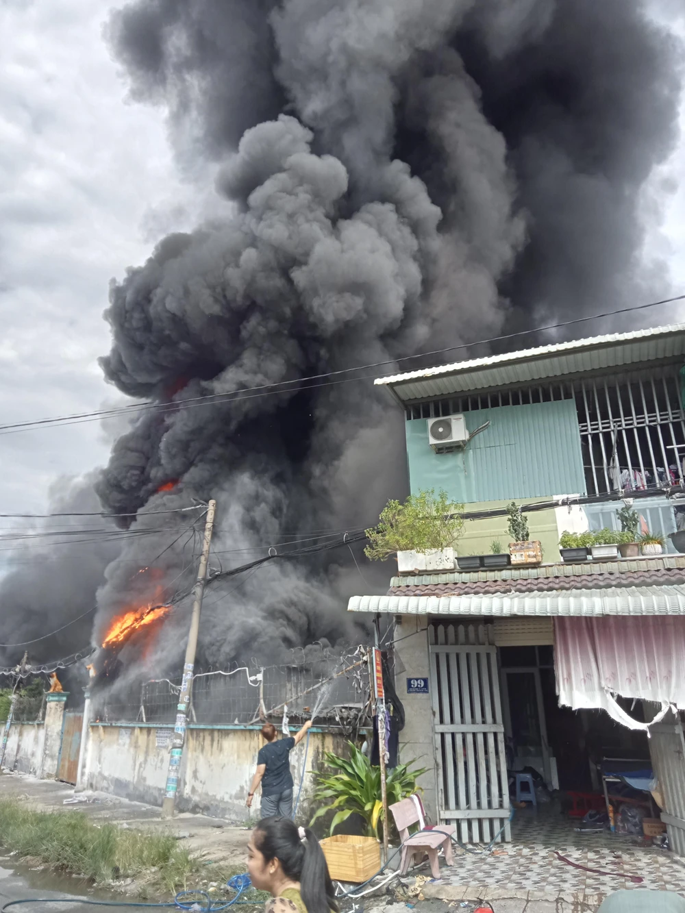 Cột khói bốc lên cao hàng trăm mét, trong khi người dân cố gắng dùng nước sinh hoạt để dập lửa. Ảnh: NT