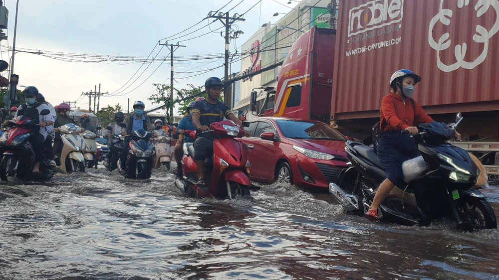 Trong khi đó, mỗi khi xe tải lớn đi qua sóng nước làm các xe máy lưu thông khó khăn. Ảnh: NT