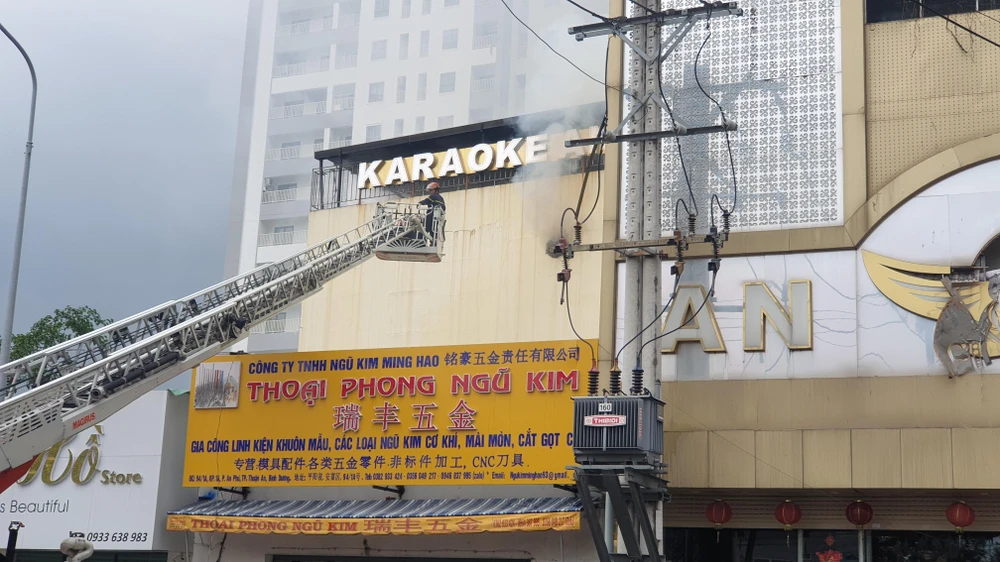 Cảnh sát đục tường để hút khói bên trong ra ngoài. Ảnh: THƠ TÂN