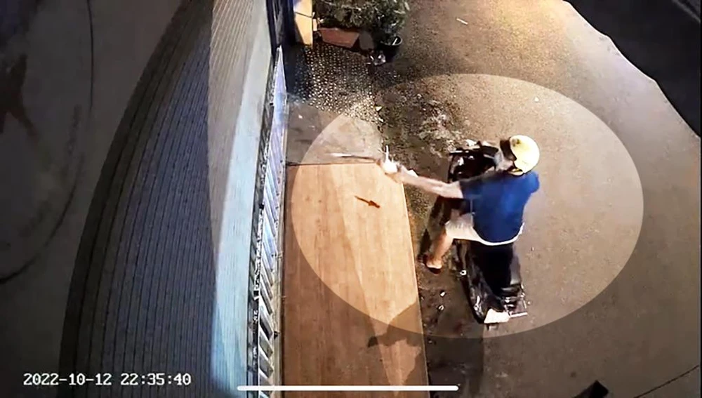 Tiếp đó, một người thanh niên cũng đi xe máy tới tạt sơn, nhớt, mắm tôm vào căn nhà. Ảnh chụp từ clip