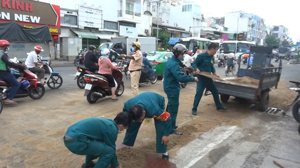 Lực lượng dân quân cùng CSGt dọn dẹp nhớt bằng cát trên đường. Ảnh: HT