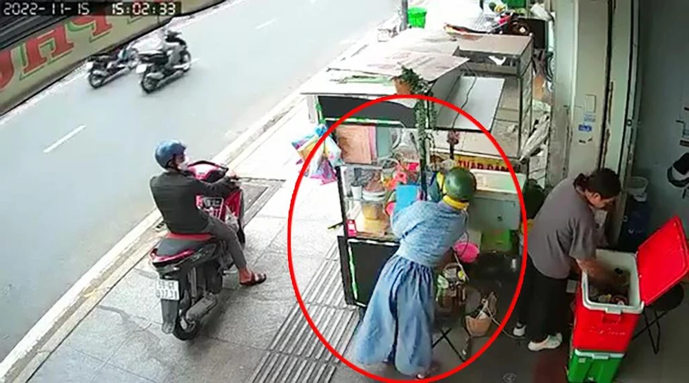 Người phụ nữ dàn cảnh lấy trộm chiếc điện thoại ngay sau lưng nữ nhân viên. Ảnh chụp từ clip