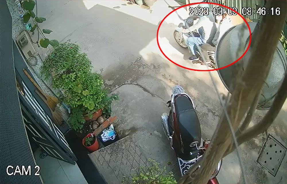 Hai thanh niên đảo một vòng trước nhà bà T trước khi trộm xe. Ảnh chụp từ clip
