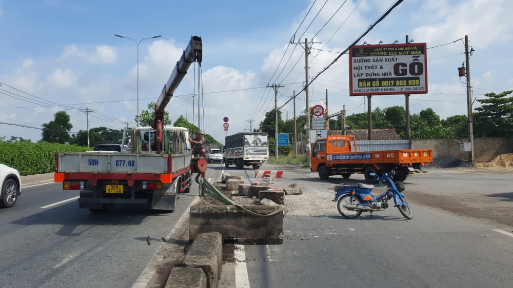 Lực lượng chức năng điều động xe cẩu tới di dời các phiến bê tông dải phân cách bị tông hỏng. Ảnh: NT
