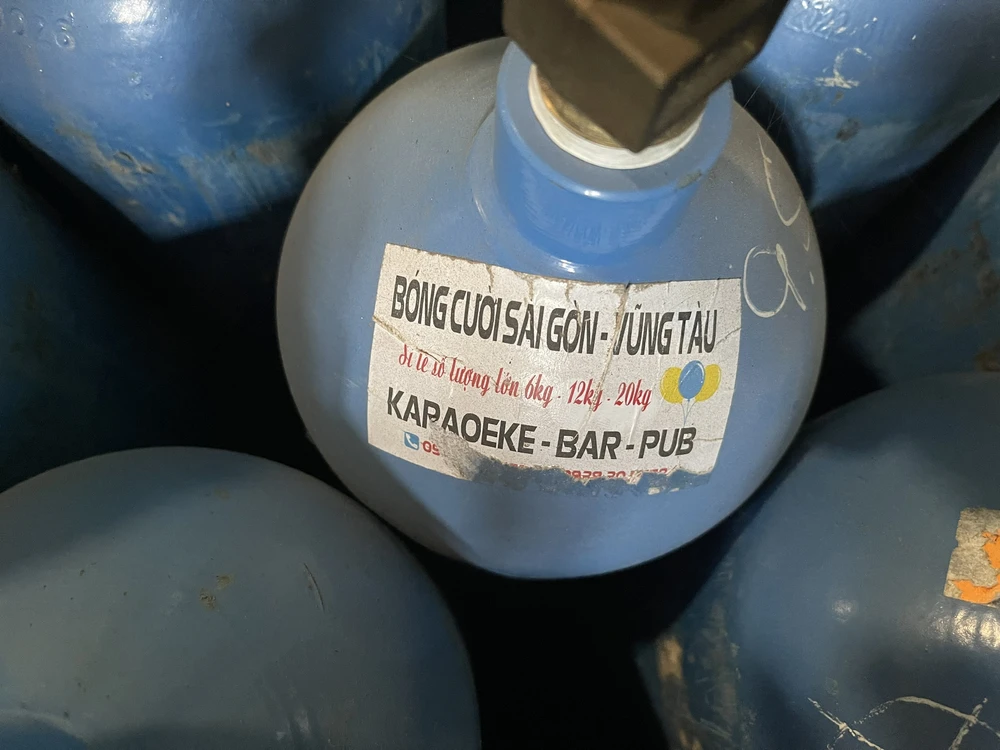 Ở kho hàng, nhiều vỏ bình có dán nhãn quảng cáo cung cấp số lượng lớn khí "cười" cho các quán bar, karaoke... Ảnh: NT