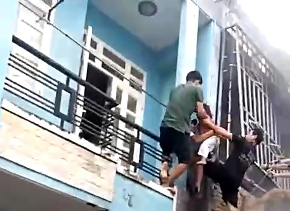 Người dân cùng lực lượng chức năng đã giải cứu ba người, trong đó có một cháu bé trong căn nhà cháy ra ngoài an toàn. Ảnh: HT