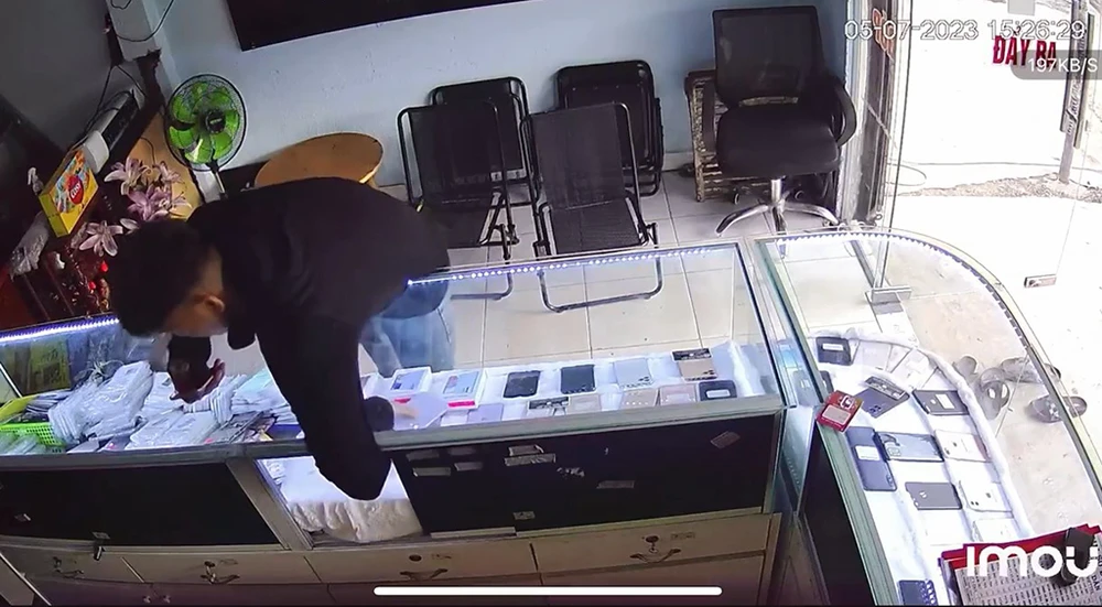 Người đàn ông thản nhiên mở tủ trưng bày, lấy đi hai chiếc điện thoại. Ảnh cắt từ clip