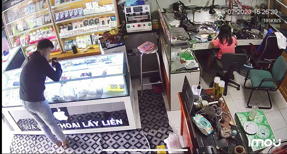 Người này thản nhiên lấy trộm dù trong tiệm có người. Ảnh cắt từ clip