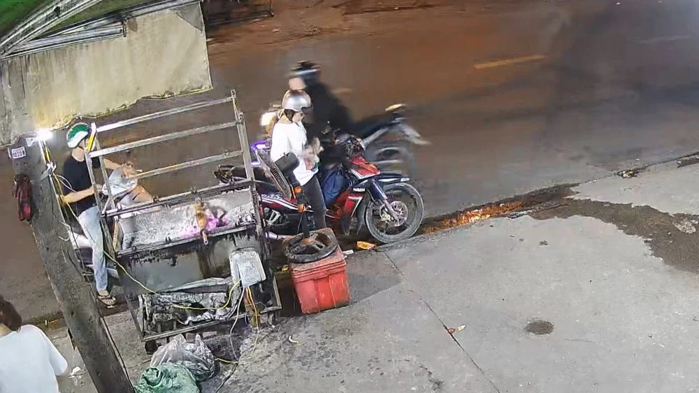 Nam thanh niên chạy xe ngược chiều, áp sát cướp giật điện thoại của cô gái đang chờ mua vịt quay. Ảnh cắt từ clip