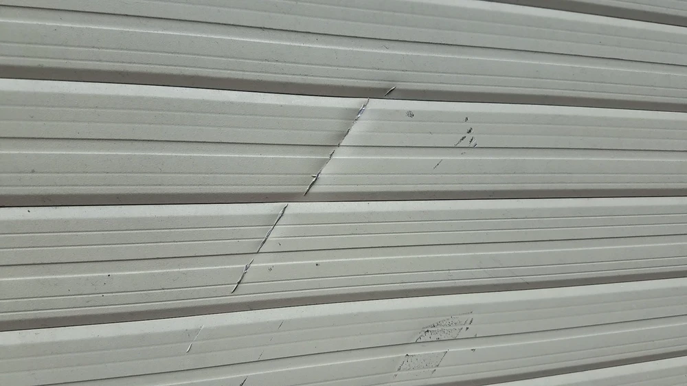 Cửa cuốn nhà anh T bị chém hư hỏng, cửa kính bên trong bị chém bể nát. Ảnh: HT