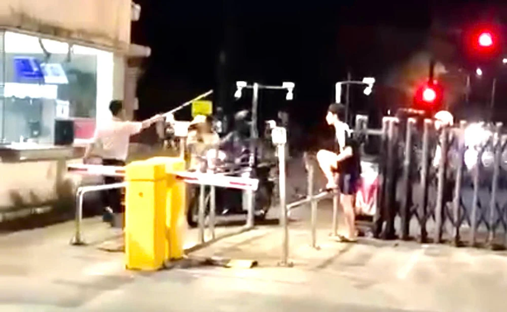 Người mang trang phục bảo vệ cầm gậy đánh nam thanh niên trước cổng ký túc xá làng đại học