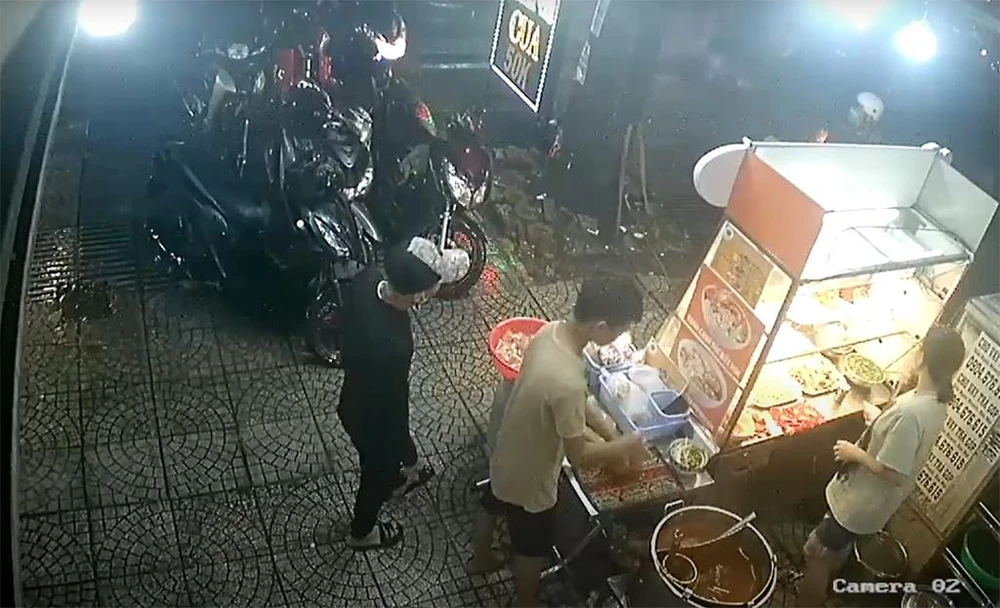 Thanh niên (áo đen) vào mua bánh canh trước khi lấy trộm xe của chủ quán. Ảnh cắt từ clip Thanh niên (áo đen) vào mua bánh canh trước khi lấy trộm xe của chủ quán. Ảnh cắt từ clip