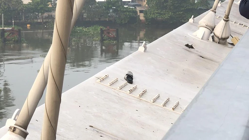 Đôi dép nam thanh niên để lại trên thành cầu. Ảnh: NY Đôi dép nam thanh niên để lại trên thành cầu. Ảnh: NY