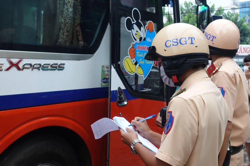 Đội CSGT Hàng Xanh lập biên bản xử phạt xe khách vi phạm ở khu vực bến xe miền Đông cũ. Ảnh: ĐC