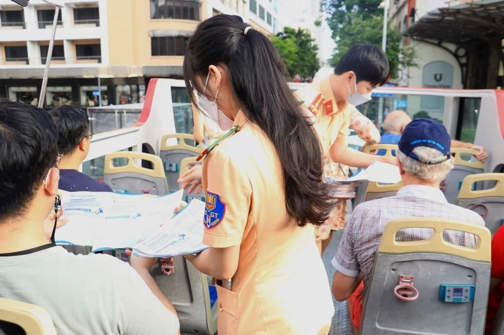 Cán bộ Phòng PC08 tuyên truyền luật giao thông cho khách nước ngoài trên xe buýt 2 tầng ở trung tâm TP.HCM. Ảnh: PC08