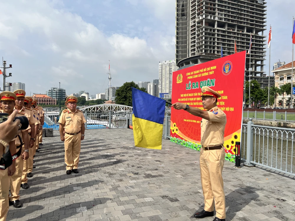 Trưởng phòng Cảnh sát đường thủy phất cờ ra hiệu xuất quân. Ảnh: NGUYỄN YÊN