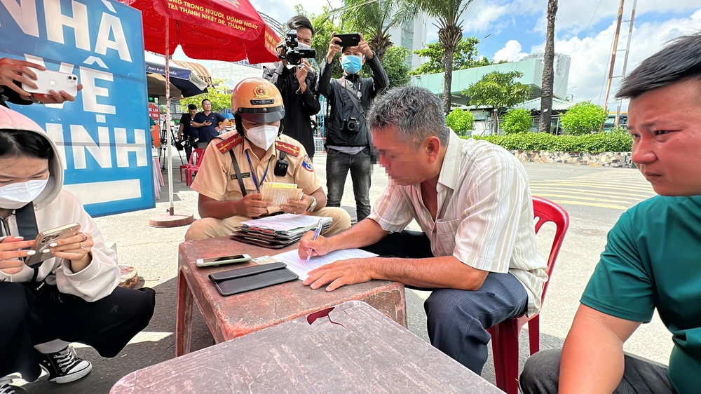 Tài xế H ký vào biên bản vi phạm hành chính và viết cam kết tuân thủ quy định giao thông đường bộ sau khi làm việc với tổ công tác. Ảnh: NY