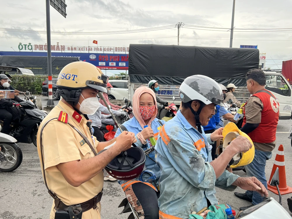 Cán bộ CSGT Tân Túc đổi nón bảo hiểm cho người dân trên đường về quê nghỉ lễ.