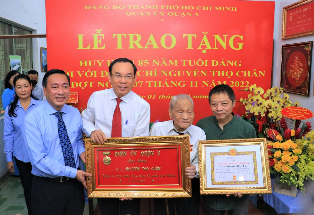 Bí thư Thành ủy TP.HCM Nguyễn Văn Nên cùng Bí thư Quận ủy quận 3 Phạm Thành Kiên trao tặng huy hiệu và chúc mừng ông Nguyễn Thọ Chân. Ảnh: VÕ THƠ