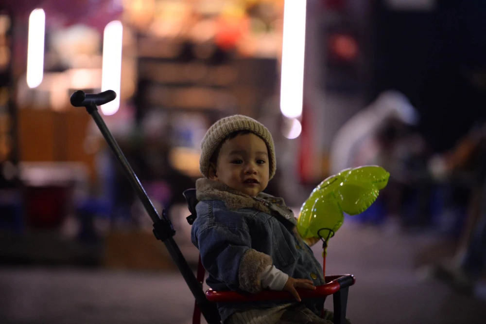 Những em bé được cha mẹ đưa cùng ra phố để đón năm mới. Ảnh: PHI HÙNG