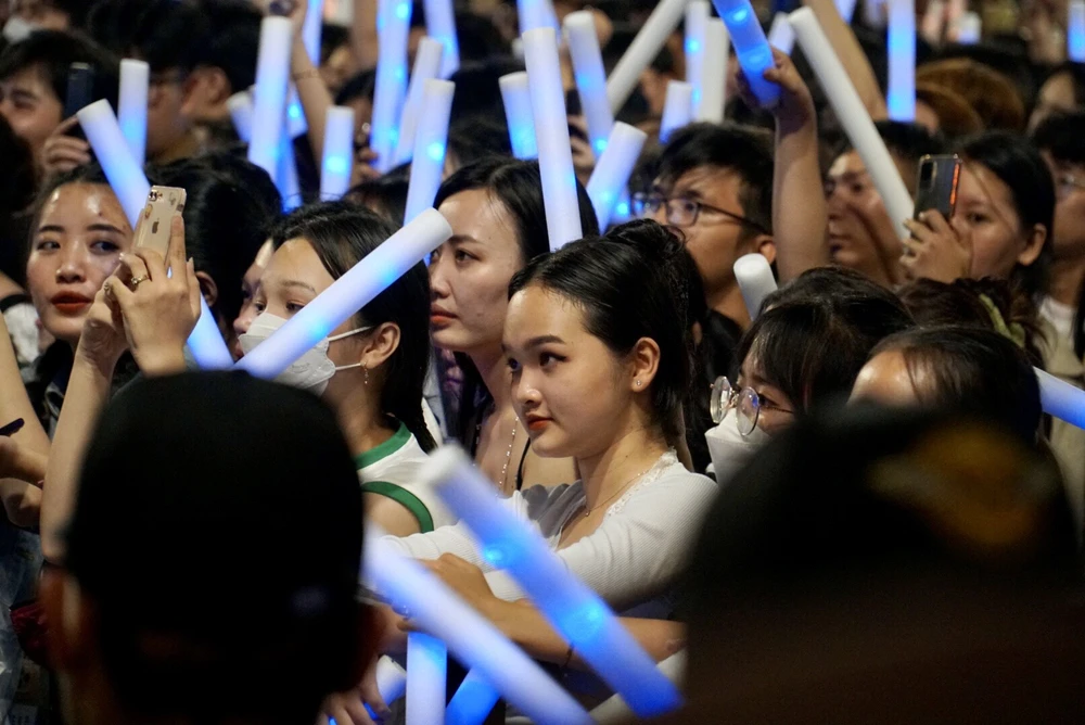 Các bạn trẻ dùng gậy sáng, flash cổ vũ dưới khán đài, khu vực trung tâm phố đi bộ Nguyễn Huệ và hai bên đường ken đặc người.
