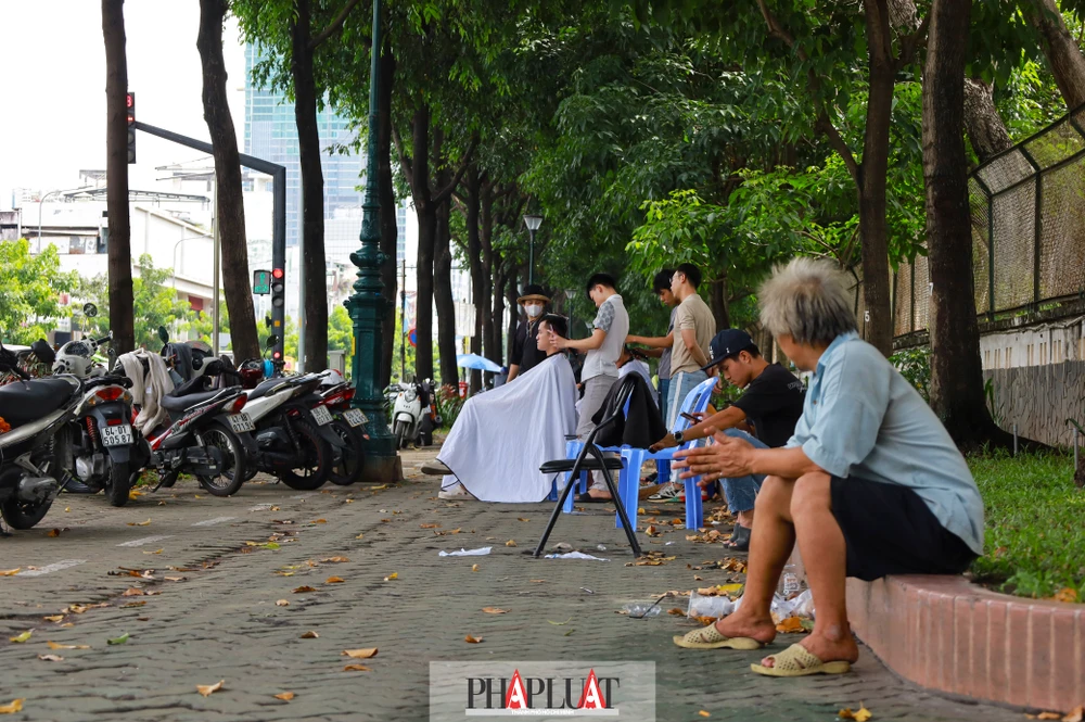 Khu vỉa hè bao bọc bên ngoài khu đất, trở thành địa điểm dừng chân của tài xế công nghệ và các hoạt động khác như hớt tóc, bán hàng rong… Ảnh: Di Linh