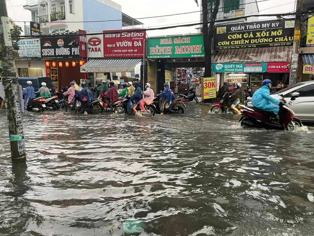 Người dân bì bõm sau cơn mưa ở quận Gò Vấp. Ảnh: TH