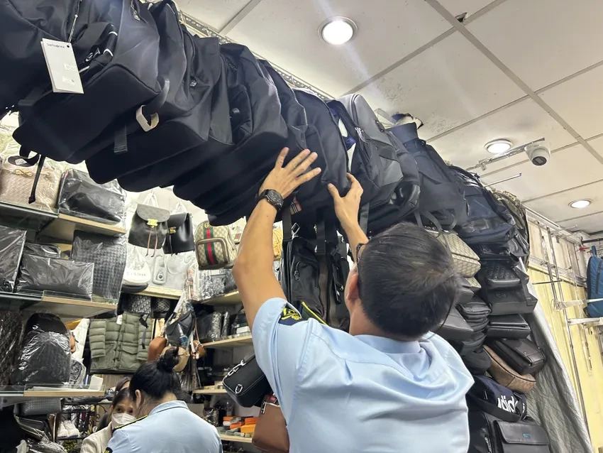 Lực lượng chức năng kiểm tra mặt hàng balo, túi xách... tại các chợ truyền thống ở TP.HCM. Ảnh: HỒNG THẮM.
